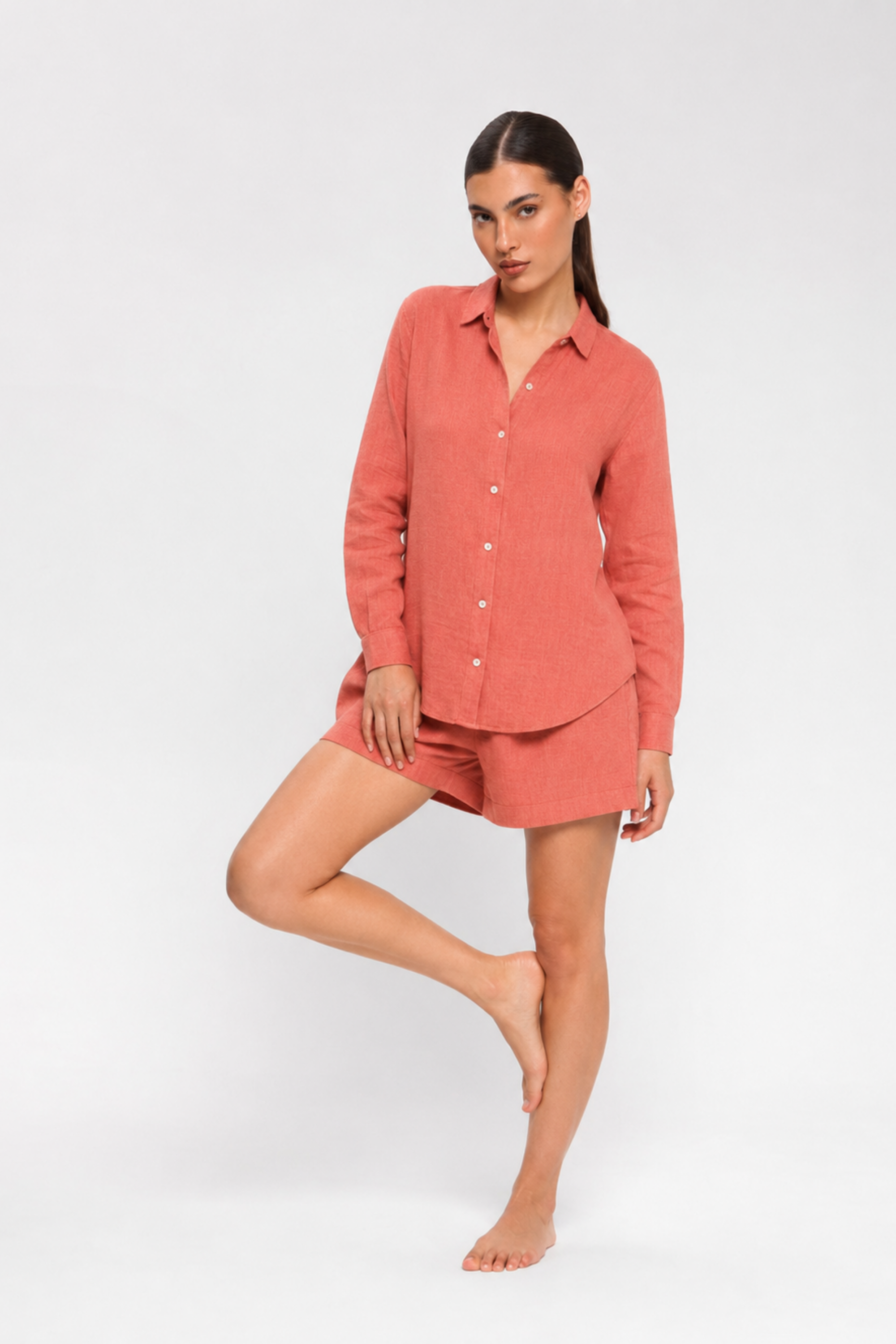 Woman sitting on a chair wearing a pink shirt and shorts by Koye in Rosewood pink bamboo-hemp. #color_Rosewood