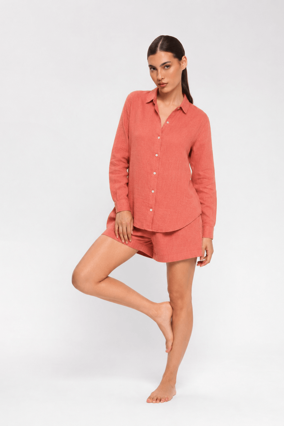 Woman sitting on a chair wearing a pink shirt and shorts by Koye in Rosewood pink bamboo-hemp. #color_Rosewood