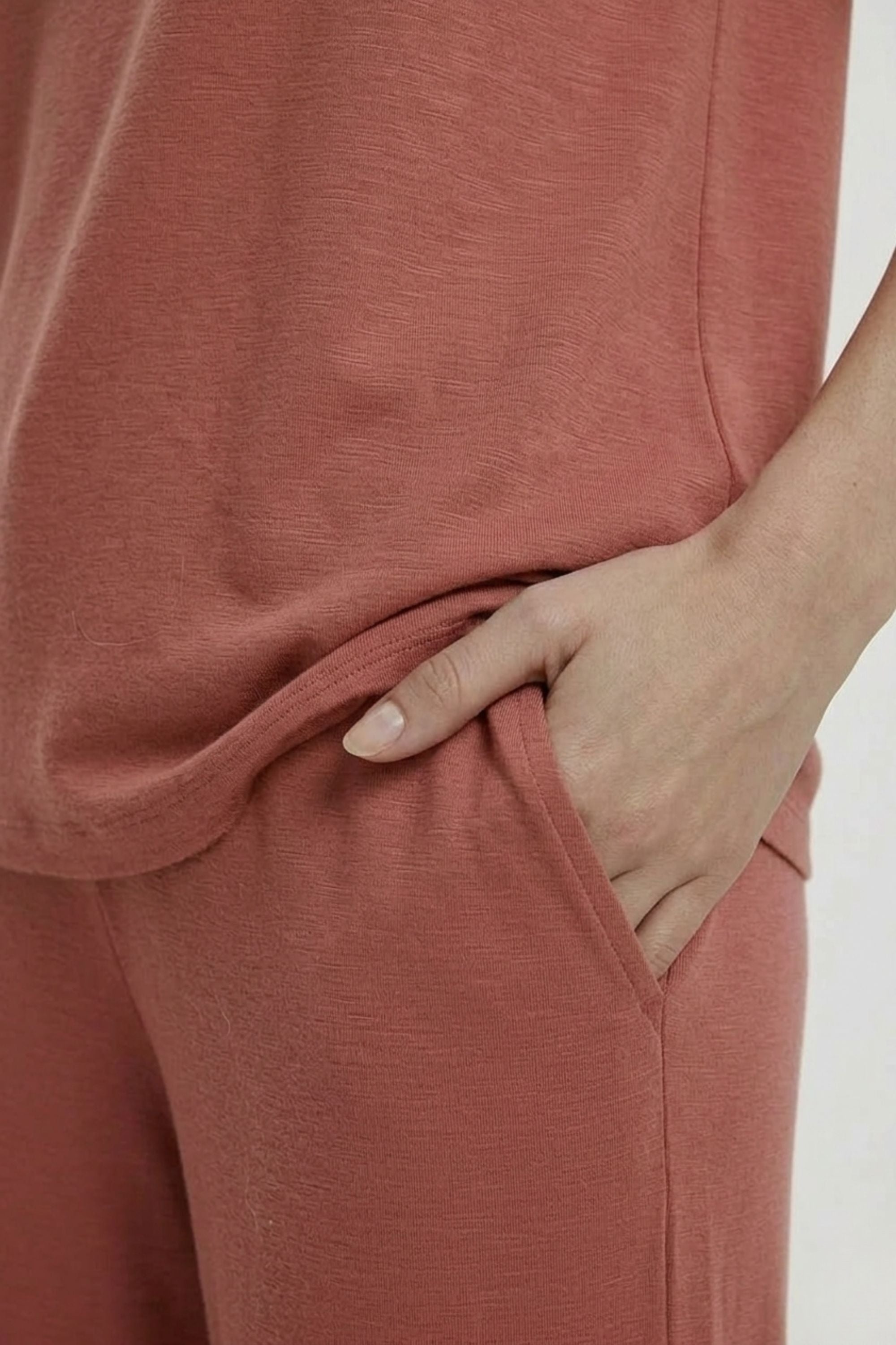 Close-up of the smooth bamboo cotton fabric and pocket detail on the Koye Ease Lounge Set. #color_Coral