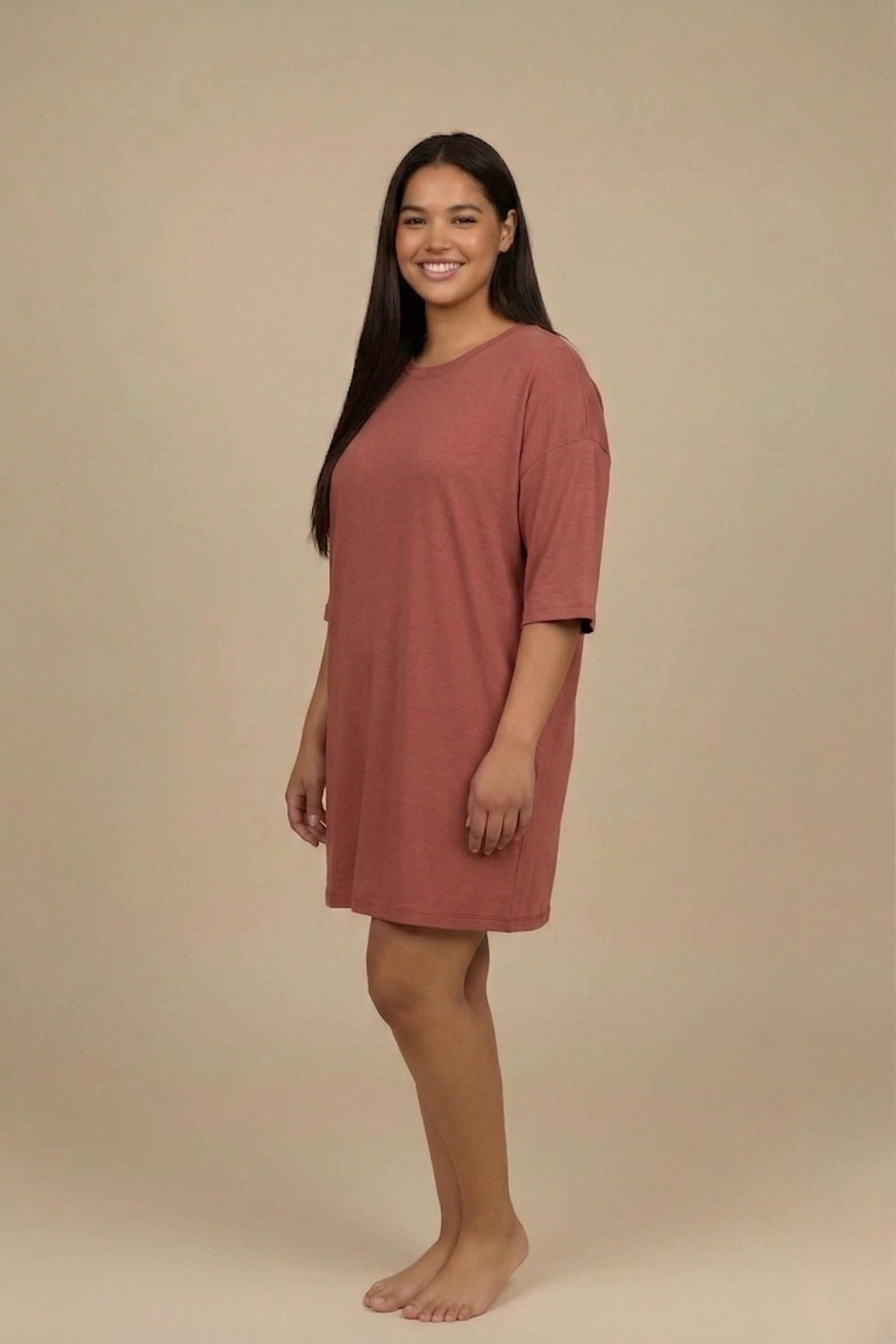 Side profile of a woman modeling the Snug Oversized Dress in Dusky Mauve, highlighting the comfortable half-sleeves and elevated loungewear style. #color_Coral